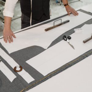 Hands of a tailor working with fabric and patterns in a workshop, showcasing traditional craftsmanship.